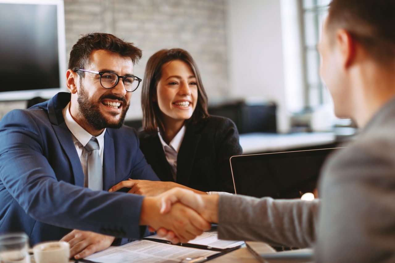 Young business couple make a deal and shake hands